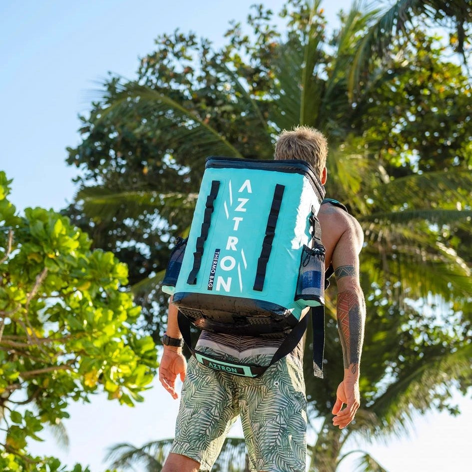 Hombre en la playa con la mochila cooler Aztron Thermo Cooler 38 litros en la espalda