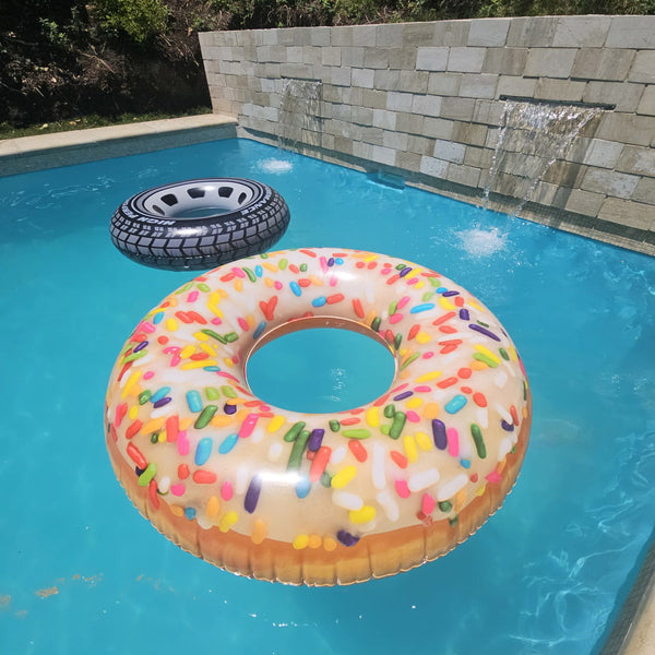 Flotador INTEX con forma de dona con chispas flotando en una piscina junto a un flotador neumático