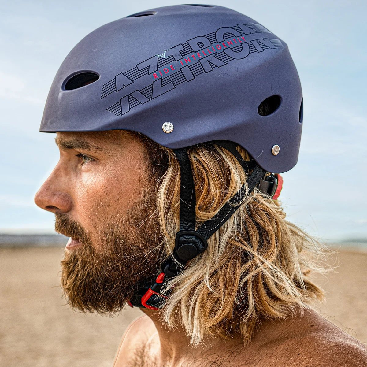 Hombre en la playa con el casco Aztron H7 para kayak y deportes acuáticos