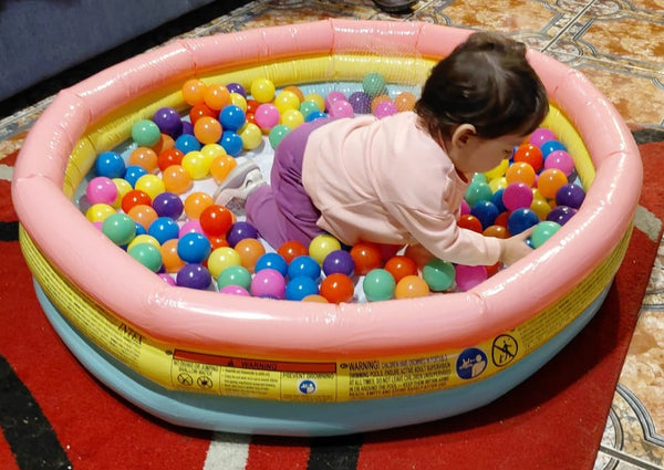 Niña jugando dentro de una piscina inflable INTEX llena de pelotas de colores
